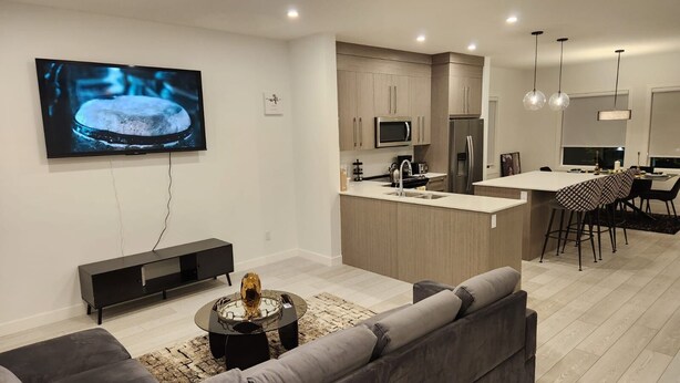 Una cocina moderna con una isla central, electrodomésticos integrados y un área de comedor con taburetes de bar.