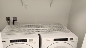 Un cuarto de lavado con dos lavadoras Whirlpool y un tendedero de metal.