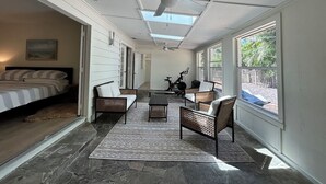 Ein geräumiges Zimmer mit Bett, Deckenventilator, Korbmöbeln und Blick ins Freie.