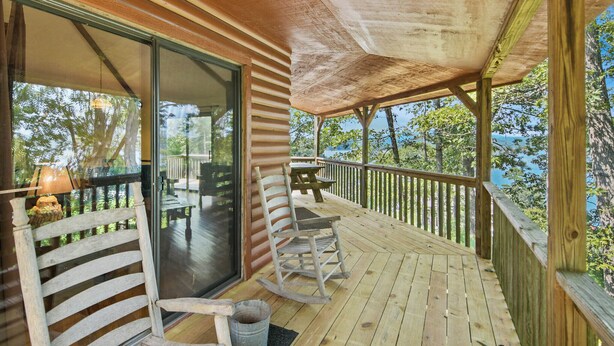 Une terrasse en bois avec une porte vitrée donnant sur un balcon, une chaise berçante et une table.