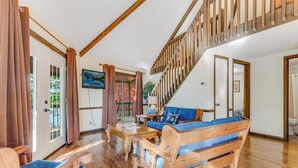 Un salon au parquet en bois, avec un canapé bleu, une table basse en bois et un escalier doté de rampes en bois.