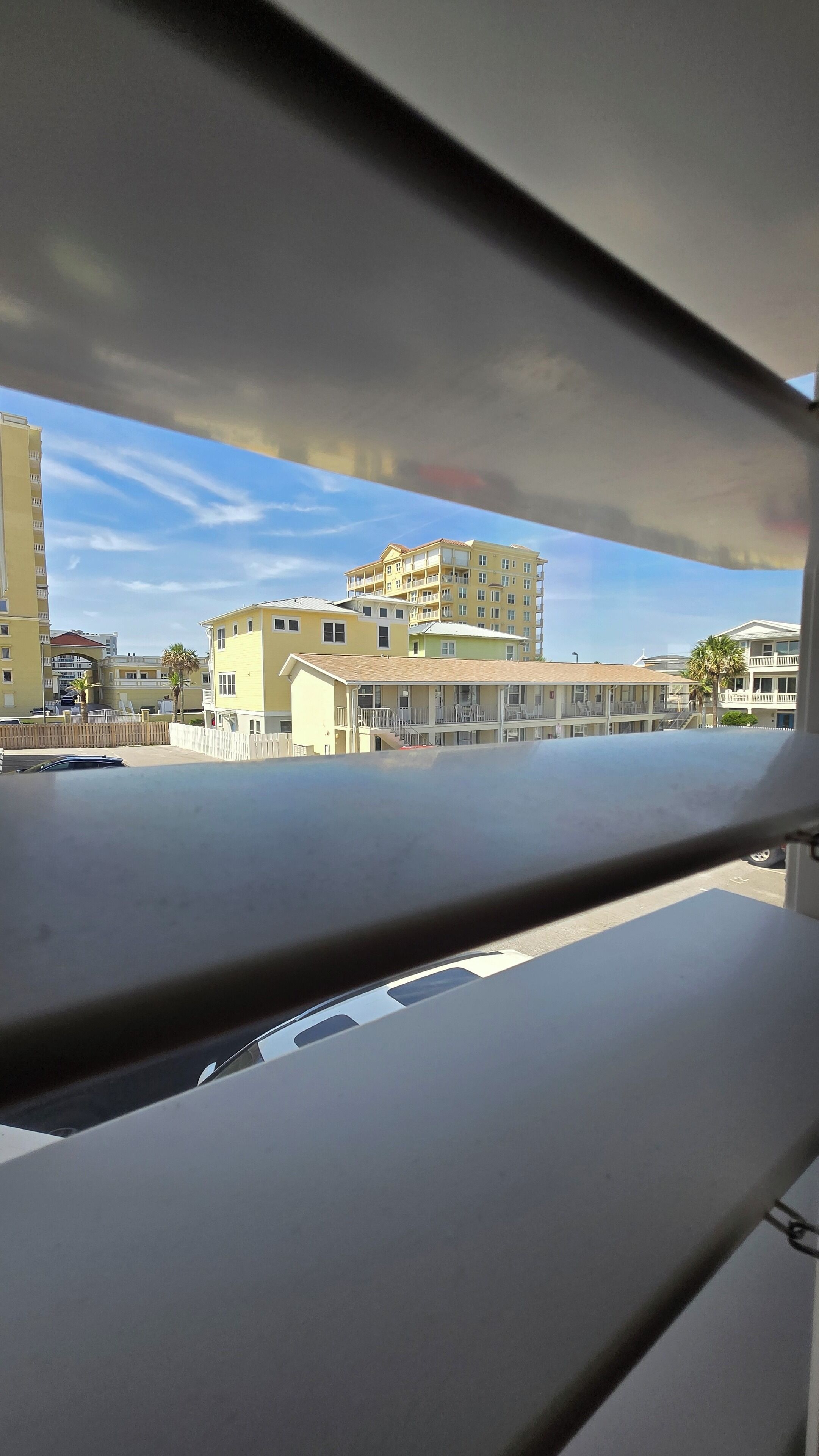Vista de un edificio de varios pisos con balcones y un área de estacionamiento al frente.