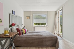 A bedroom with a bed, a window with blinds, a radiator, a desk with a lamp, and a picture on the wall. - A peaceful oasis near the beach and forest (Hundested)
