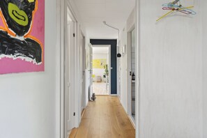 Ein Flur mit Holzboden, weißen Wänden und einer Tür am Ende, die in einen anderen Raum führt.
