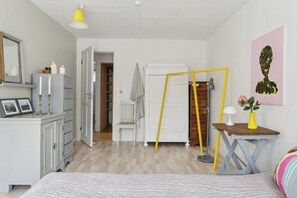 Ein Schlafzimmer mit Bett, Kommode, Spiegel und einer Tür zu einem Flur.