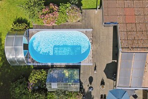 An aerial view of a swimming pool with a wooden deck, surrounded by greenery and a house with a tiled roof. - Holiday paradise with pool near Havnsø Beach (Føllenslev)