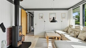 Una sala de estar moderna con estufa de leña, un sofá, una mesa y vistas al exterior.