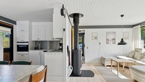 Una cocina moderna con armarios blancos, una estufa central y un comedor con mesa y sillas.