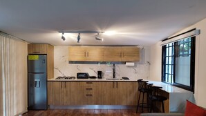 Una cocina moderna con armarios de madera, estufa integrada y un amplio ventanal.