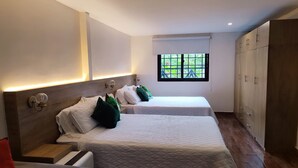 Habitación de hotel con dos camas, ventana con vistas, suelo de madera y un armario.