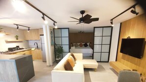 Een moderne woonruimte met een keuken, een bank, een eethoek en een slaapkamer.