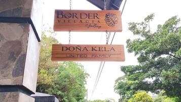 A sign for 'Border Villages Valley' and 'Dona Kela United Family' hanging from a structure.