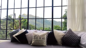 Una cama con muchas almohadas y vistas a un paisaje montañoso a través de amplios ventanales.