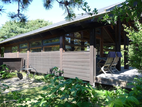 A cabin with a covered porch, a small deck, and a chair.