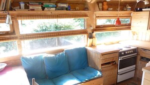 A cozy cabin interior with a wooden bench, a stove, and a window overlooking greenery. - Cozy cottage close to the beach (Liseleje)