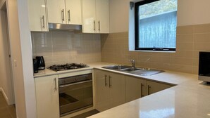 A modern kitchen with white cabinets, stainless steel appliances, and a window above the sink. - Blues Air 3A - Thredbo (Thredbo)