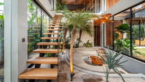 A modern interior with a wooden staircase, a curved seating area, and a glass wall offering a view of the outdoors.