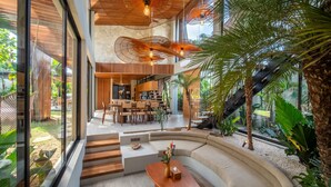 A modern interior with a curved seating area, a dining space, and a staircase leading to an upper level.