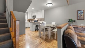 Eine moderne Küche mit weißen Schränken, ein Essbereich mit Tisch und Stühlen sowie eine Treppe mit Holzwertungen.