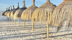 A row of thatched umbrellas on a sandy beach. - APARTBEACH PARADIS PARK VUE SUR LA PLAGE (La Pineda)