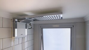 Ein Badezimmer mit weißen Fliesen, einer Duschkabine und einer Tür mit Milchglasfenster.