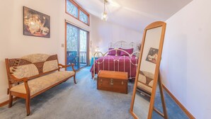 Ein Schlafzimmer mit einer hölzernen Bank, einem Metallbettgestell, einer Holzkommode und einem großen Spiegel.
