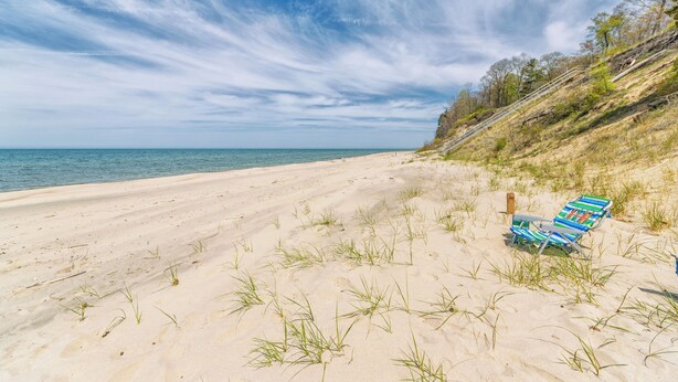 Een strand met heldere lucht, een zandstrand en een stoel.