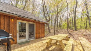 Een houten chalet met terras, barbecue en picknicktafels.