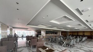A spacious lobby with a bar area, seating arrangements, and a modern ceiling design. - Grand Travello Hotel Bekasi (Bekasi)