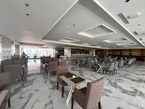 Un vestíbulo amplio con zona de bar, diferentes disposiciones de asientos y un diseño de techo moderno.