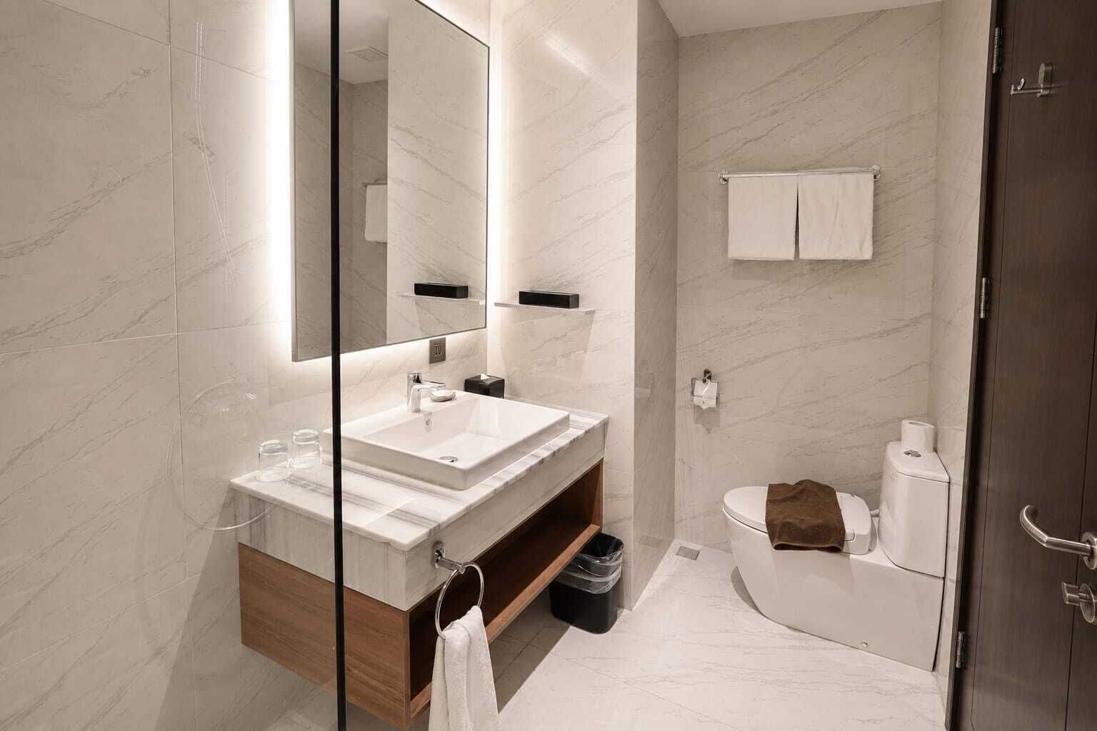 Un baño moderno con un espejo grande, un lavabo y un inodoro.