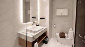 A modern bathroom with a large mirror, a sink, and a toilet.