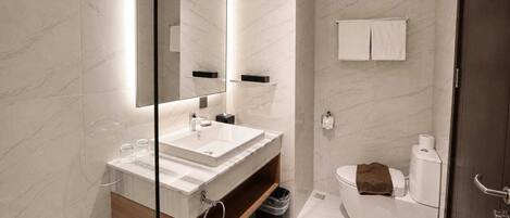 Un baño moderno con un espejo grande, un lavabo y un inodoro.