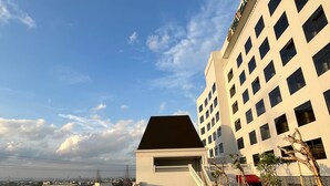 A swimming pool with a clear view of a building with multiple windows and a balcony. - Grand Travello Hotel Bekasi (Bekasi)