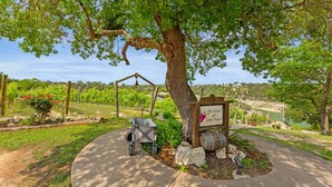 Een bord met de tekst 'The Villas at Lake Travis' onder een grote boom, een kinderwagen en een vat.