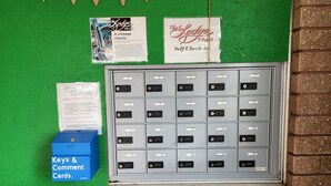 A row of numbered hotel room keys, a sign for self check-in, and a box for keys and comment cards. - Family Suite - Economy (Garden City)