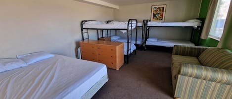 A room with bunk beds, a wooden dresser, a striped armchair, and a painting on the wall.