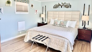 A bedroom with a large bed, two bedside tables, a wall-mounted lamp, and a radiator. - House Acadia at Gallagher`s Travels (Bar Harbor)