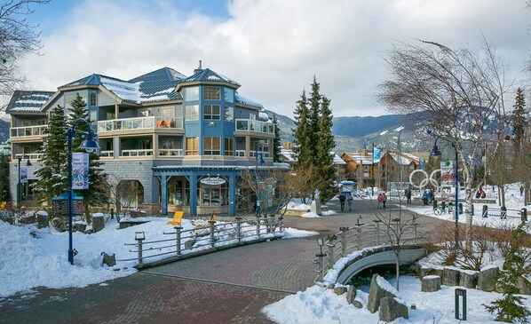 A hotel with a ski lift, snow-covered surroundings, and a mountain backdrop.
