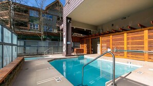 A swimming pool with a wooden deck and a lifebuoy. - 2BR + Loft + Sofabed | Tyndall Stone Lodge | Epic Village Location | Mountain Views | Pool & Hot Tub (Whistler)