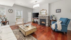 A living room with a fireplace, a television, and a blue armchair. - Stately 5-bedroom estate in beautiful Prince Edward with fitness room, AC (Prince Edward)