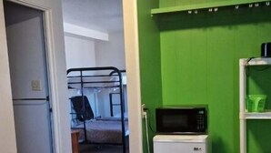 A room with a bunk bed, a microwave, and a refrigerator.