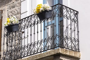 A balcony with wrought iron railings and flower pots. - "Antiquarian's Loft" (Tempio Pausania)