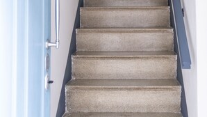 A staircase with a handrail, leading to a door.