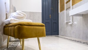 A bathroom with a yellow ottoman, a towel rack, and a blue door.