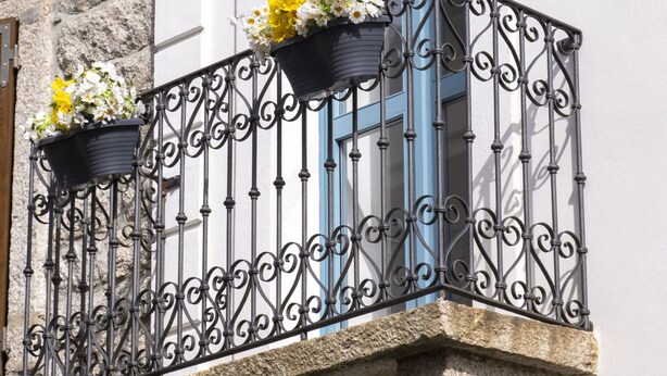 Un balcon orné de balustrades en fer forgé et de jardinières.
