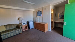 A compact living space with a sofa, a small cabinet, a microwave, and a refrigerator.