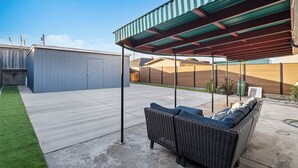 Un patio couvert avec un canapé en osier et un sol en béton.