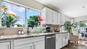 A modern kitchen with white cabinets, a granite countertop, and a view of the outdoors through a large window. - 4BR, 2BA with Heated Pool, BBQ, Fire pit in Port St. Lucie (Port St. Lucie)