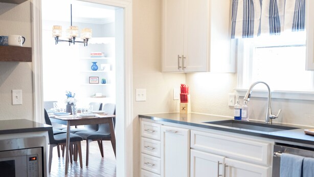 A modern kitchen with white cabinetry, a built-in microwave, and a dining area with a table and chairs. - The Bluebonnet - Pet-Friendly Historic 3BR Home in Downtown McKinney (McKinney)